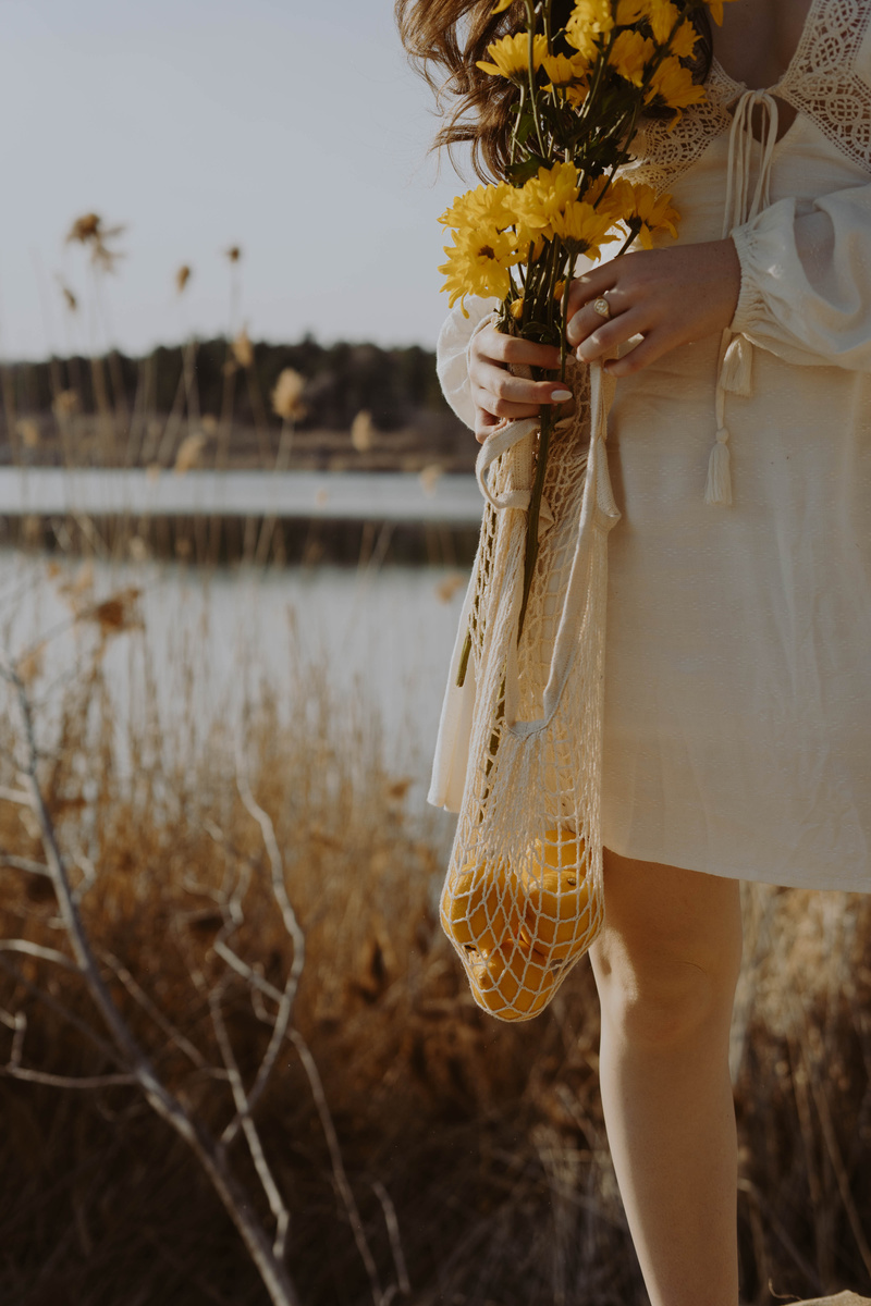 Woman in White Dress Holding Yellow Sunflower